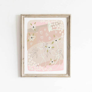 Soft blush pink abstract floral print with whimsical hearts, framed and styled against a white wall.