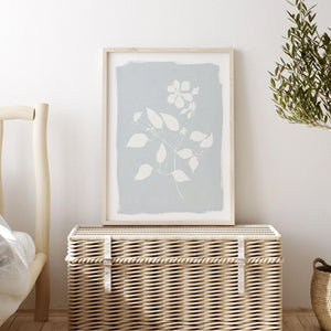 Close-up of white botanical silhouette print on soft blue background, styled in vintage wood frame