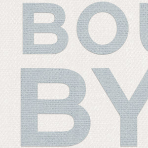 Close-up of blue “BOUY BYE” text on textured off-white fabric background, showing detailed woven texture of the coastal typography print.