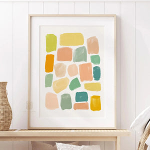 Colorful abstract wall art print featuring hand-painted geometric shapes in warm peach, mustard yellow, sage green, and teal. Framed in a light wood frame, styled in a neutral modern space.