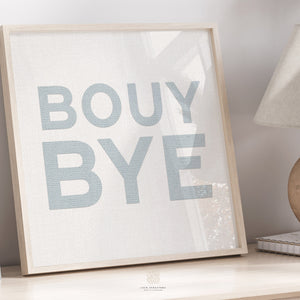 Playful blue coastal art print with “BOUY BYE” text, styled in a cozy neutral space with natural wood accents.