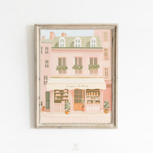 French storefront art print in soft pastel pinks and sage green, framed and styled on a white wall for elegant home, nursery, or gallery wall decor.