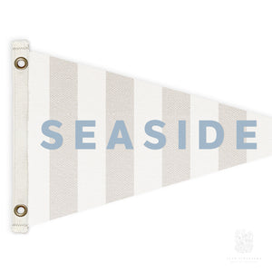 Close-up of a striped beige and white canvas pennant flag with the words "Seaside" in blue, perfect for kids' rooms, bathrooms, and other nautical-inspired spaces.