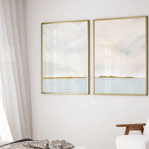 Pretty landscape watercolours featuring a calm lake, and billowy cloudy skies hung on a white wall in golf frames in a bedroom.