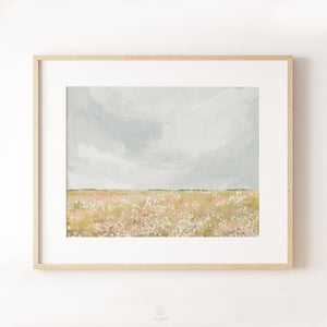 Framed horizontal wildflower meadow print styled in a minimalist interior with pale wood frame and soft wall lighting.