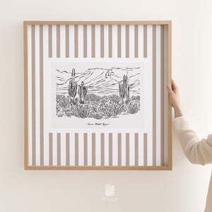 Large striped Sonoran Desert cactus illustration in neutral tones, shown framed in a light wood frame and held up for size reference.