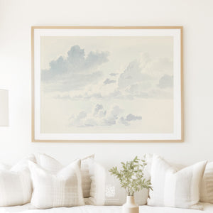 Vintage cloud wall art framed in light wood, styled above a white sofa with soft textured pillows and a neutral-toned vase, perfect for relaxed living spaces or coastal-inspired interiors.
