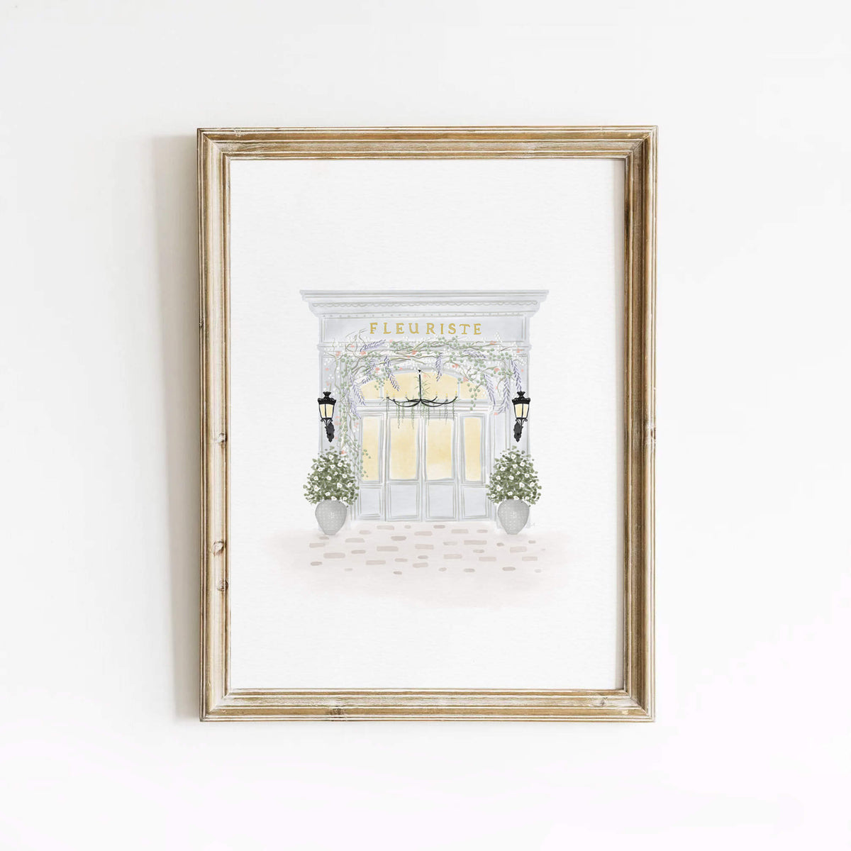 Fleuriste art print featuring a soft Parisian flower shop illustration, framed in light wood and styled against a white wall for elegant home decor.