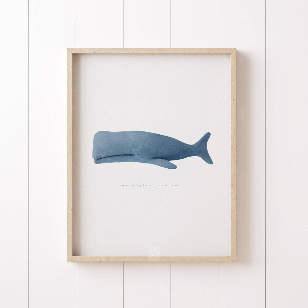 Framed minimalist whale art print in a light wood frame, styled against white shiplap walls. Ideal for nursery, beach house, or modern coastal room styling.