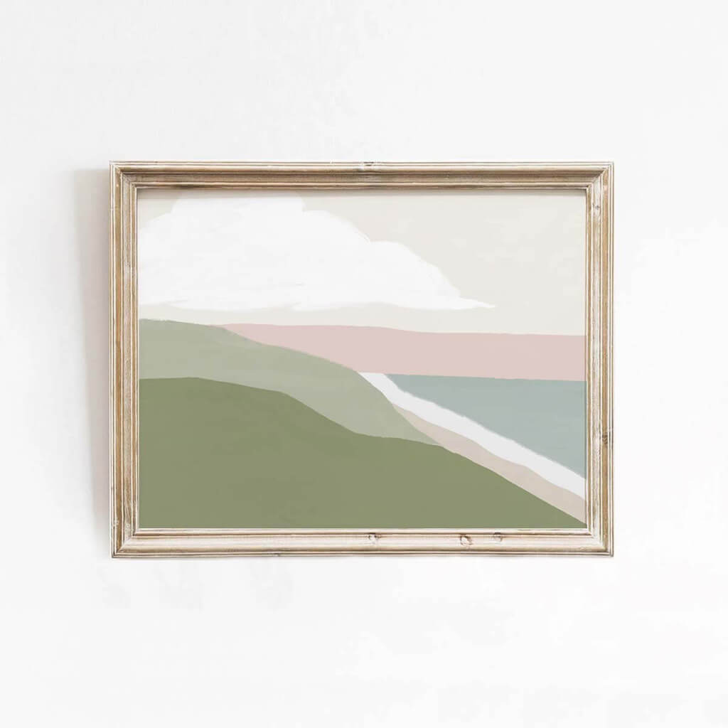 Pretty landscape print in pastel colours of a beach, green hills, a sunset and cloud. By Leah Straatsma