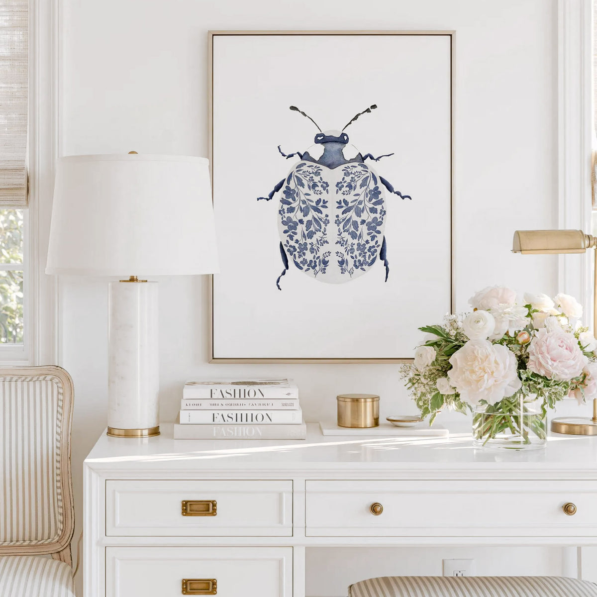 Blue Ladybug Print featuring a navy beetle with delicate floral-patterned wings, displayed in a gold frame above a white desk.