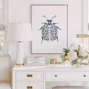 Blue Ladybug Print featuring a navy beetle with delicate floral-patterned wings, displayed in a gold frame above a white desk.
