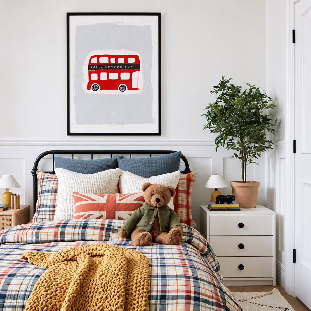 Printable 'Jolly London Town' red double decker bus nursery art, displayed in a mockup over a child's bed with plaid bedding and a Union Jack pillow.